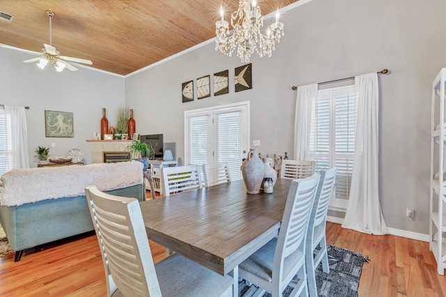 dining room featuring visible vents, light wood-style floors, wooden ceiling, a fireplace, and crown molding