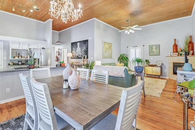 dining space with a fireplace, crown molding, wood ceiling, and light wood-style floors