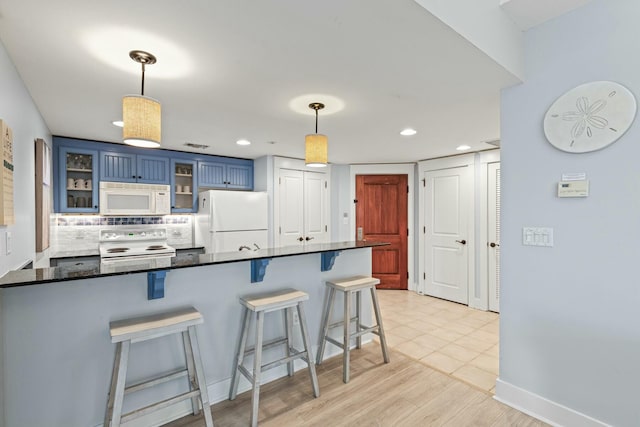 kitchen with white appliances, glass insert cabinets, a kitchen breakfast bar, blue cabinets, and backsplash