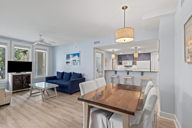 dining room featuring a ceiling fan, baseboards, visible vents, and light wood finished floors