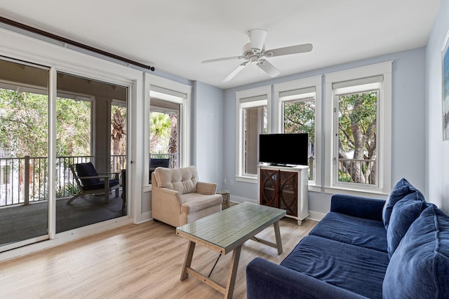 living room with light wood-style flooring, plenty of natural light, baseboards, and ceiling fan