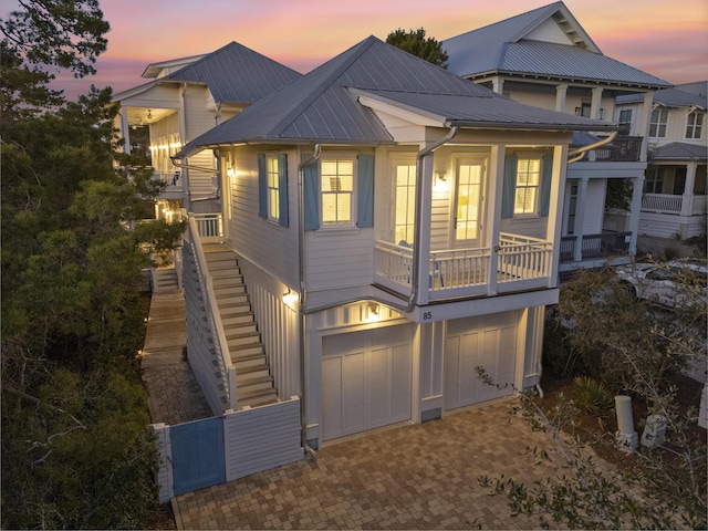 view of front of property featuring a garage, decorative driveway, metal roof, and stairs