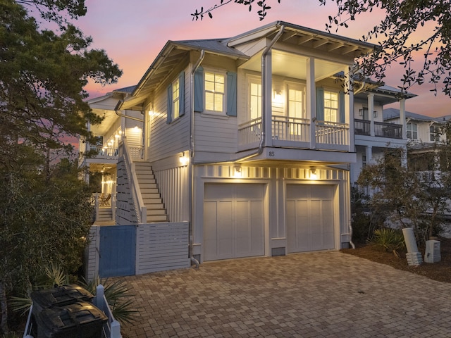 view of front of home featuring a garage, decorative driveway, stairway, and covered porch