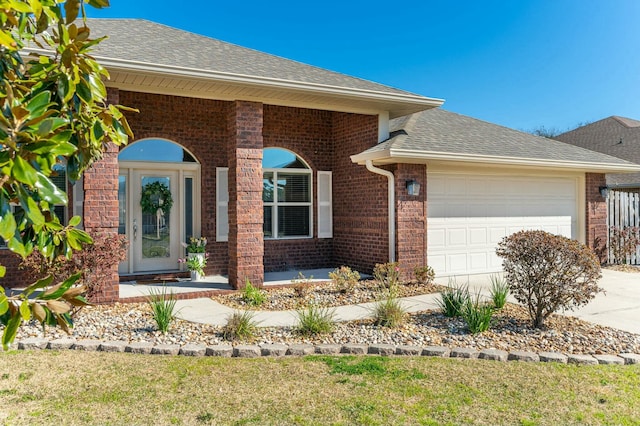 view of front of house with a garage, driveway, roof with shingles, and brick siding