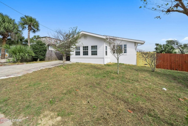 single story home featuring driveway, a front yard, and fence