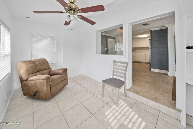 305 S Wells St, Panama City Beach, FL 32413 - living area with light tile patterned floors, baseboards, visible vents, and a ceiling fan