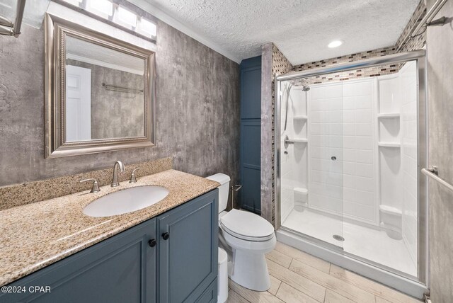 305 S Wells St, Panama City Beach, FL 32413 - bathroom featuring a textured ceiling, toilet, wood finished floors, vanity, and a stall shower