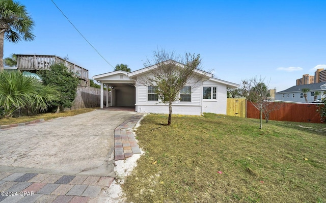 view of front of house with a carport, concrete driveway, fence, and a front lawn