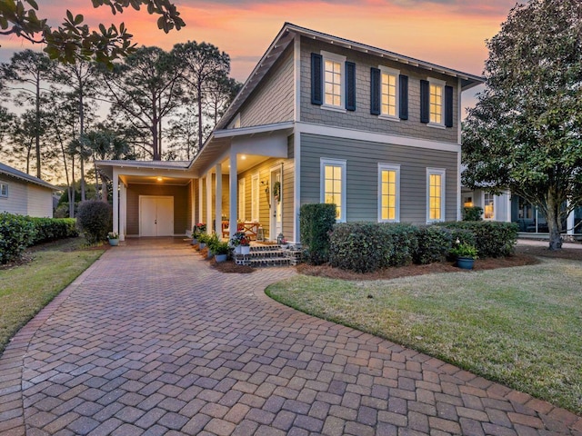 view of front facade with an attached carport, decorative driveway, and a front yard