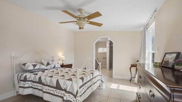 bedroom with light tile patterned floors, baseboards, multiple windows, and arched walkways