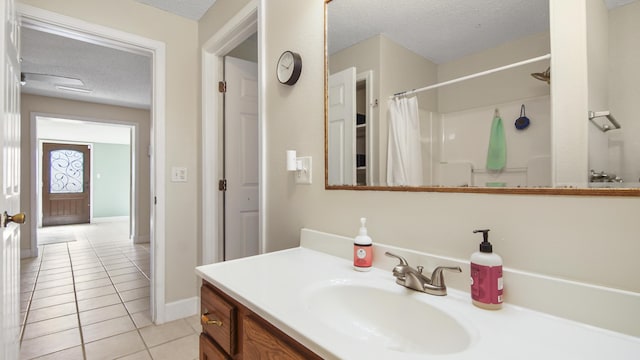 bathroom featuring a shower with shower curtain, a textured ceiling, vanity, tile patterned flooring, and baseboards