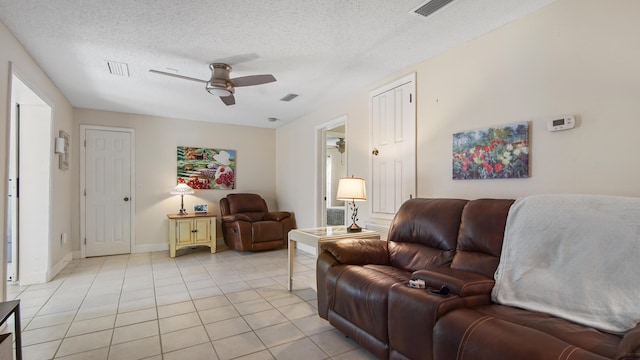 living room featuring a textured ceiling, visible vents, light tile patterned flooring, and a ceiling fan