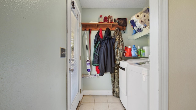 clothes washing area featuring light tile patterned floors, a textured ceiling, separate washer and dryer, laundry area, and baseboards