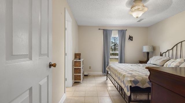 bedroom featuring visible vents, a textured ceiling, baseboards, and light tile patterned flooring