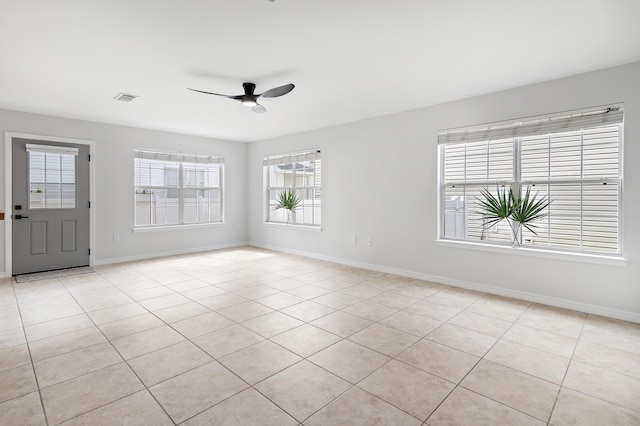 empty room featuring ceiling fan, light tile patterned floors, visible vents, and baseboards