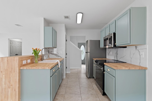 kitchen featuring black electric range oven, stainless steel microwave, visible vents, light tile patterned flooring, and a sink