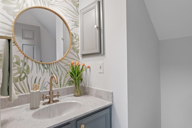 bathroom with lofted ceiling, a textured wall, and vanity