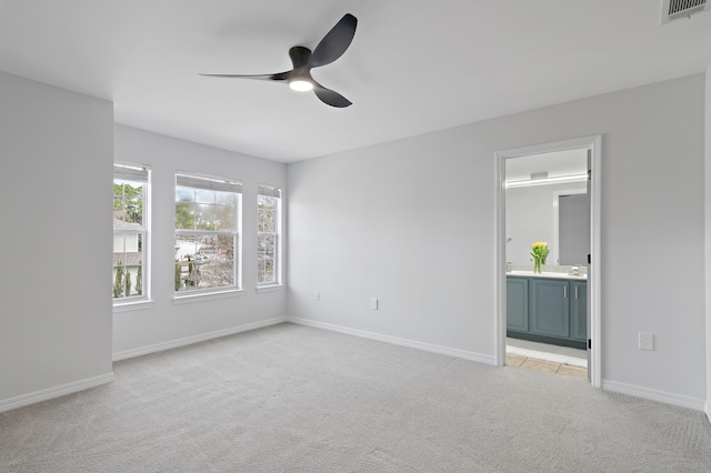 empty room with baseboards, visible vents, a ceiling fan, and light colored carpet