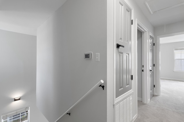 hallway featuring baseboards, an upstairs landing, and light colored carpet