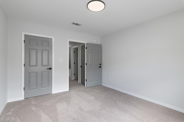 unfurnished bedroom with visible vents, light carpet, and baseboards