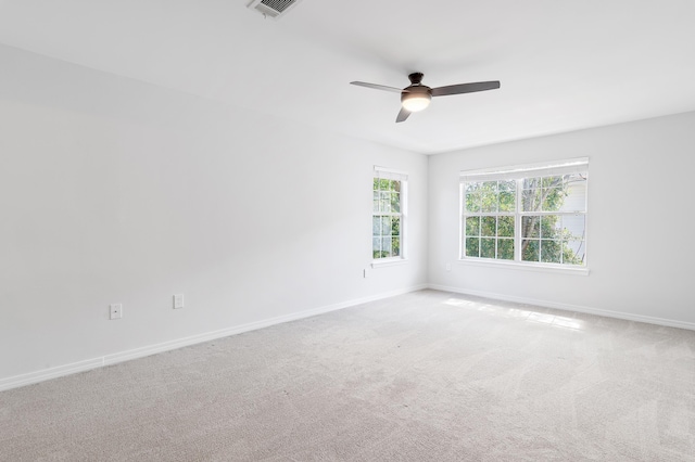 empty room with ceiling fan, carpet flooring, visible vents, and baseboards