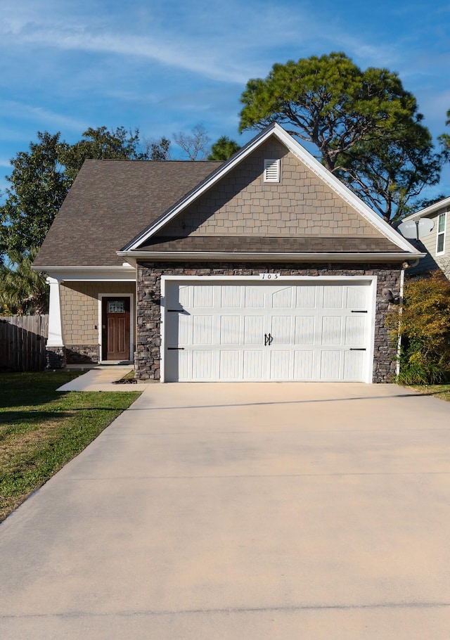 view of front of home with a garage, stone siding, fence, and concrete driveway