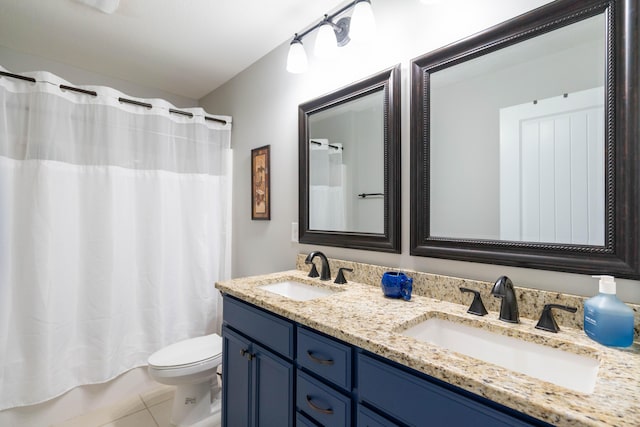 bathroom with double vanity, tile patterned flooring, a sink, and toilet