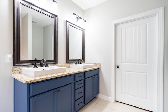 full bath with baseboards, double vanity, a sink, and tile patterned floors