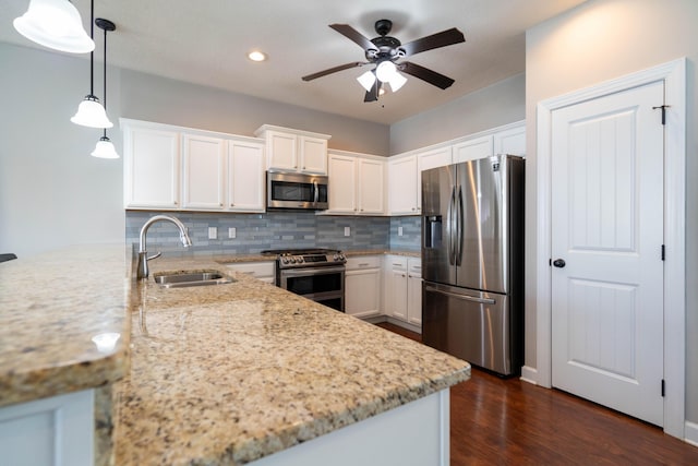 kitchen featuring decorative backsplash, white cabinets, a peninsula, stainless steel appliances, and a sink