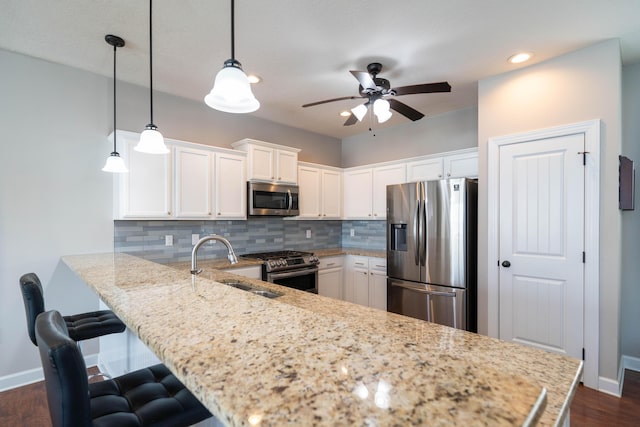 kitchen featuring stainless steel appliances, backsplash, white cabinetry, and a peninsula