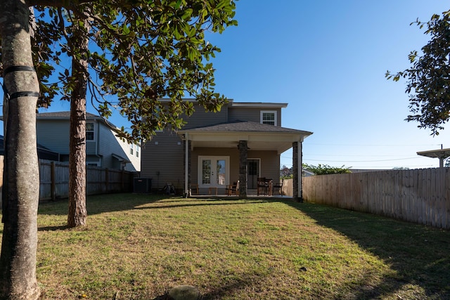 rear view of property with ceiling fan, a yard, french doors, and a fenced backyard