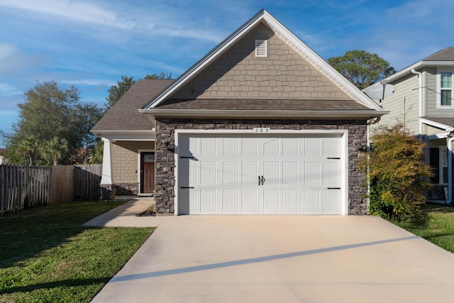 view of front of house featuring concrete driveway, stone siding, an attached garage, fence, and a front lawn