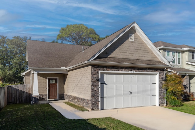 view of front of property with roof with shingles, an attached garage, fence, stone siding, and driveway