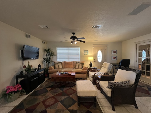 living room featuring a textured ceiling, ceiling fan, light tile patterned floors, and visible vents