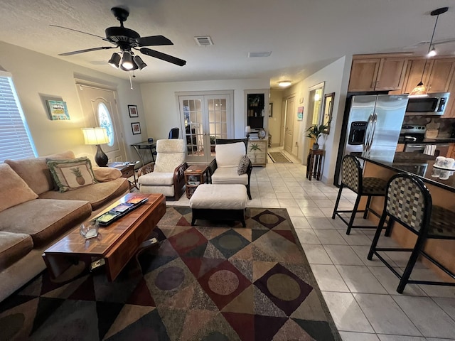 living room with visible vents, light tile patterned flooring, a ceiling fan, and french doors