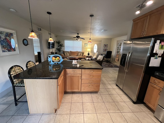 kitchen featuring light tile patterned flooring, stainless steel refrigerator with ice dispenser, a breakfast bar area, and open floor plan