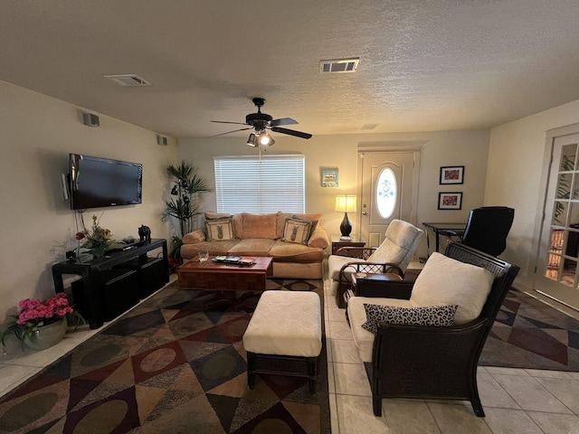 living area featuring a wealth of natural light, visible vents, a textured ceiling, and light tile patterned floors