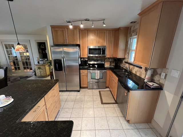 kitchen with tasteful backsplash, dark stone counters, stainless steel appliances, a sink, and light tile patterned flooring