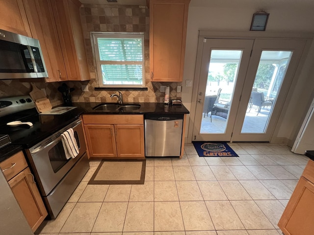 kitchen featuring a sink, appliances with stainless steel finishes, a wealth of natural light, tasteful backsplash, and dark countertops