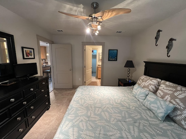 bedroom with a ceiling fan, visible vents, ensuite bath, and light tile patterned floors