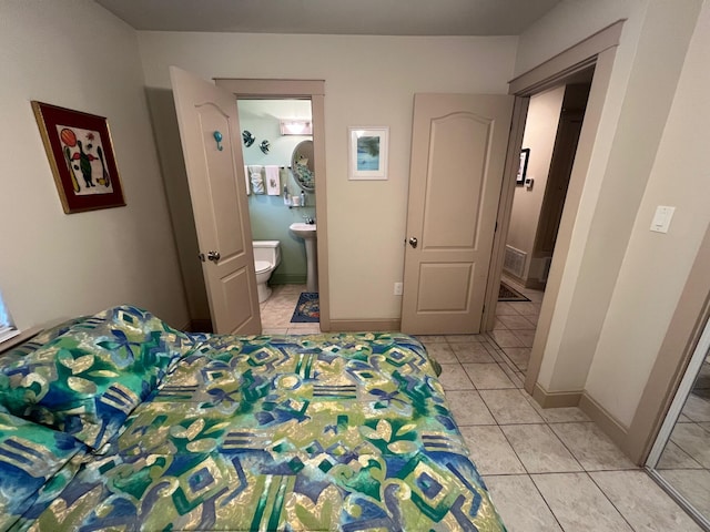 bedroom with light tile patterned flooring, ensuite bath, and baseboards