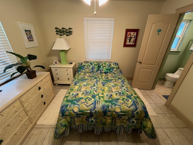 bedroom featuring light tile patterned floors, baseboards, and connected bathroom