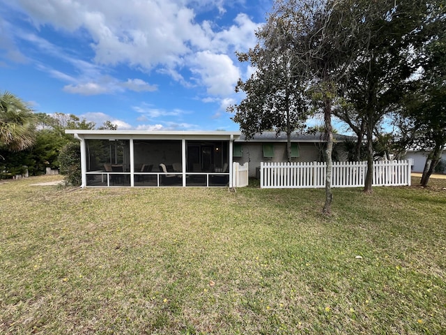 back of house featuring a lawn, fence, and a sunroom