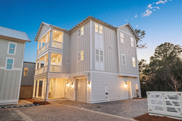 view of front facade with a balcony, an attached garage, decorative driveway, and board and batten siding