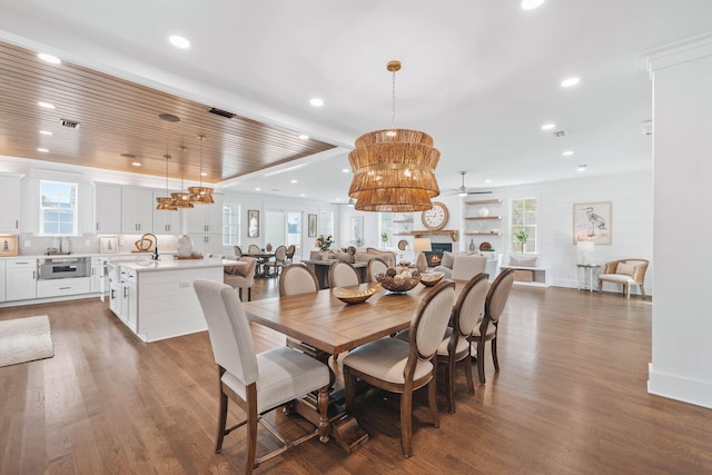 dining room with recessed lighting, a warm lit fireplace, visible vents, and wood finished floors