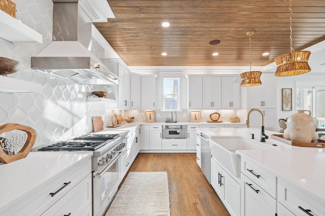 kitchen featuring wood ceiling, appliances with stainless steel finishes, light countertops, wall chimney range hood, and a sink