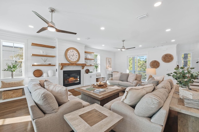 living area with ornamental molding, plenty of natural light, wood finished floors, and visible vents