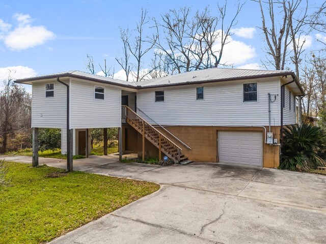 view of front facade with metal roof, a garage, stairs, concrete driveway, and a front yard