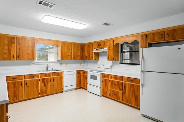 kitchen featuring under cabinet range hood, white appliances, a sink, visible vents, and light countertops