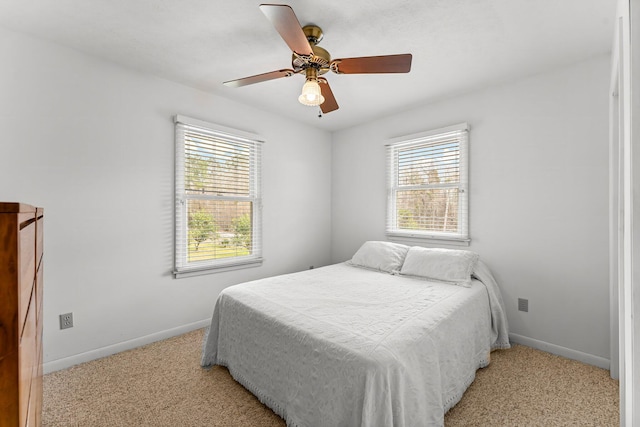 bedroom with light carpet, ceiling fan, multiple windows, and baseboards